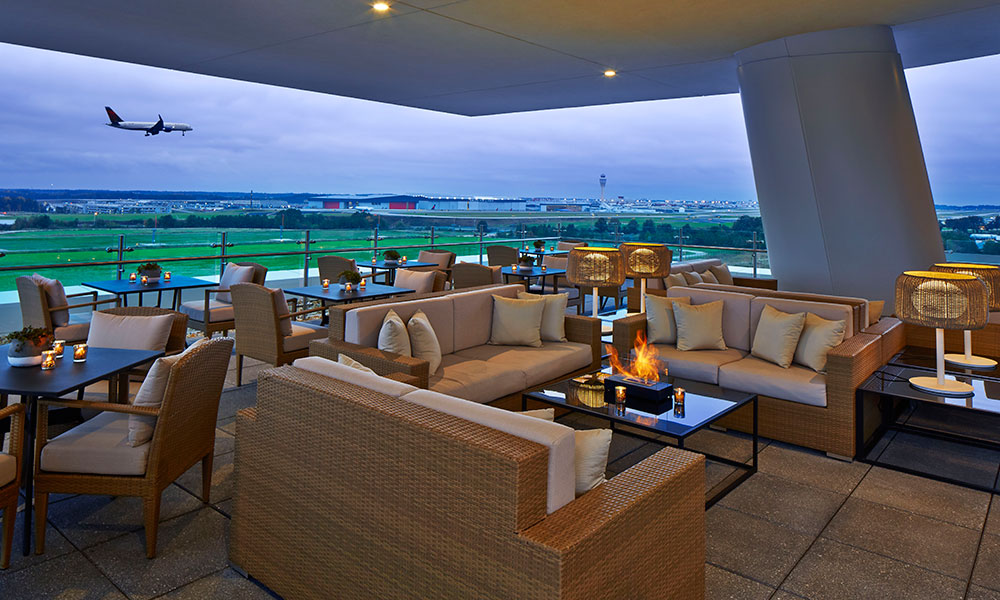 Outdoor rooftop lounge with plane taking off in the background